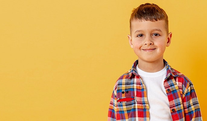 Smiling boy in plaid shirt against yellow background. Ad text: "Top Trends Style. Shop Now.