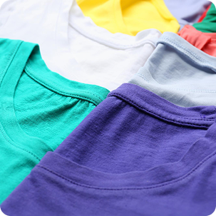 Close-up of a stack of folded children's t-shirts in various bright colors: white, yellow, purple, and green. Text overlay reads Kid's Fashion Clothing.